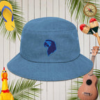 Blue denim bucket hat with an embroidered parrot head design on a wooden background with tropical elements.
