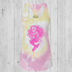 A women's racerback tank top featuring a pink mermaid graphic on a pastel tie-dye background of yellow, pink, and white, shown against a plain rustic wood background.