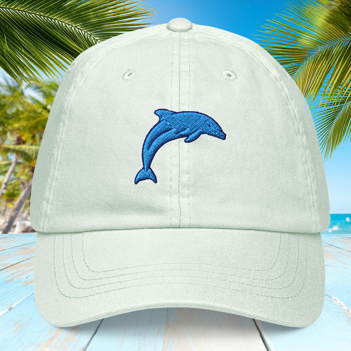 Pastel yellow cap with blue dolphin design on a beach background