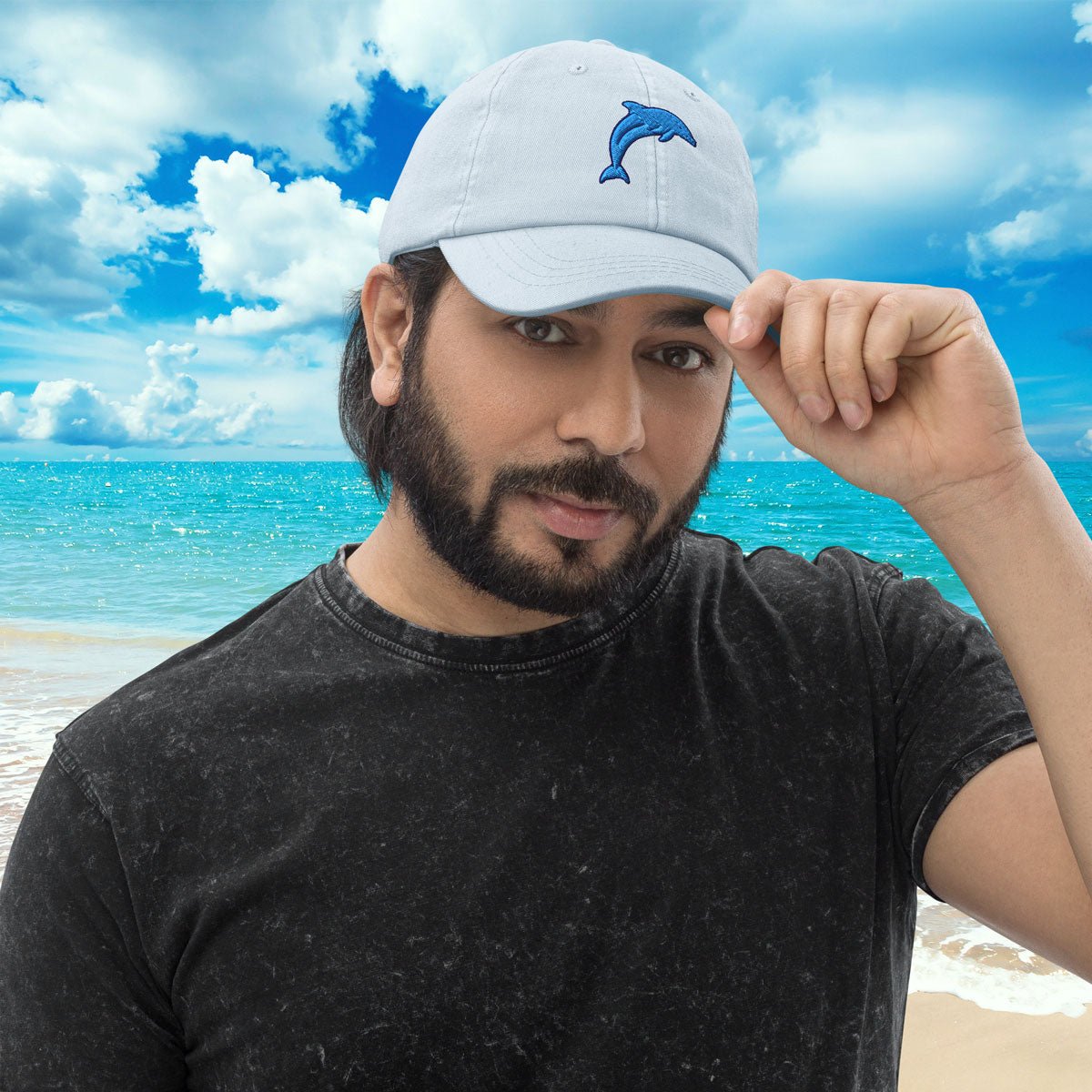 Man wearing a light blue Pastel Dolphin Baseball Hat with an embroidered dolphin logo on a beach