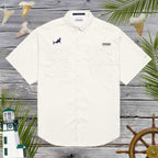 White shirt with shark design on a wooden background with lighthouse and palm leaves
