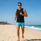Dude wearing Blue shorts with 'Fintastic Athletics' branding, and a black tank top, jogging on Miami Beach 