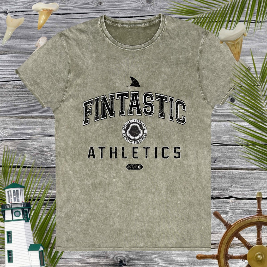 Green t-shirt with 'Fintastic Athletics' text on a wooden background with decorative elements.