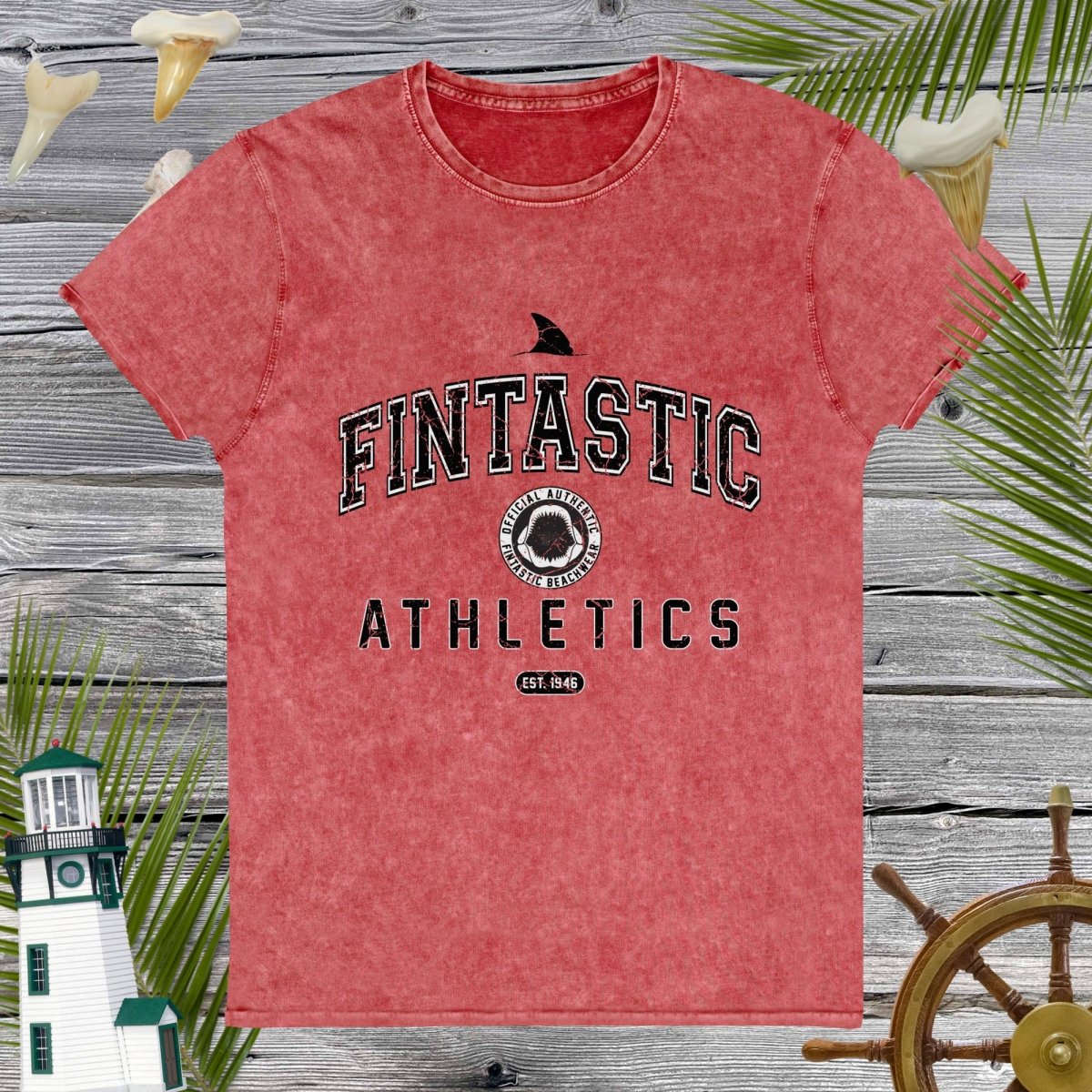 Red t-shirt with 'Fintastic Athletics' text on a wooden background with decorative elements.