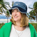 Person wearing a blue Embroidered Manatee bucket hat with text, standing in front of palm trees and the ocean.
