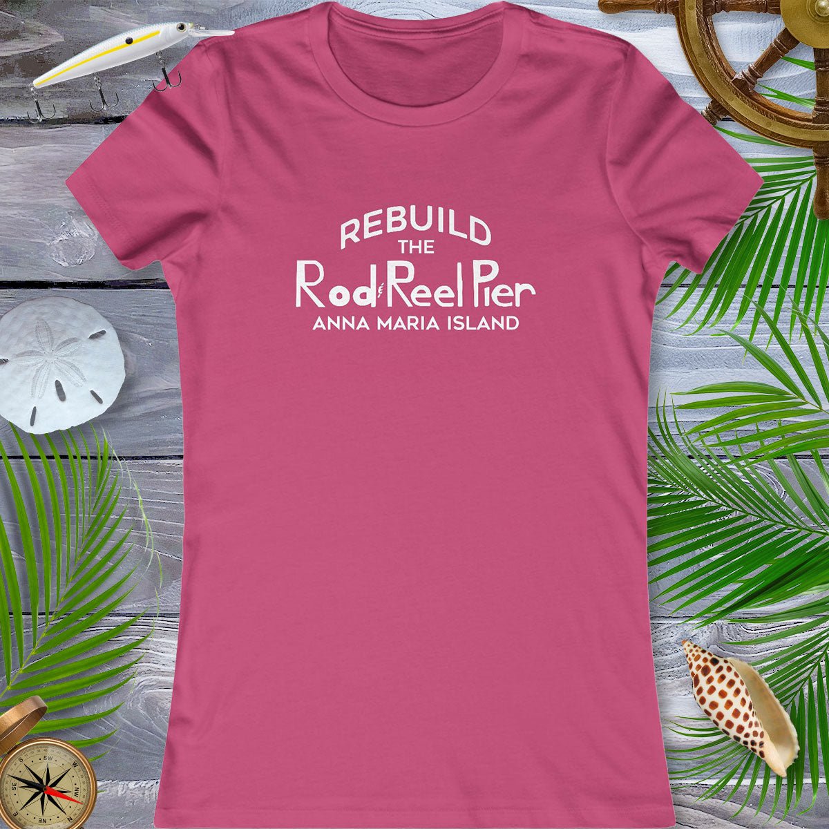 Pink t-shirt with text on a wooden surface with beach-themed decorations