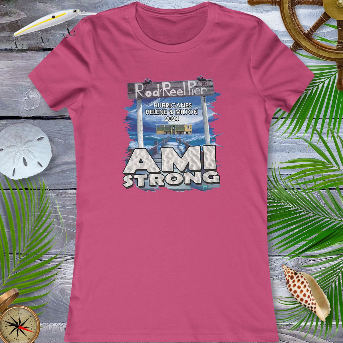Pink t-shirt with 'AMI Strong' graphic on a wooden surface with beach elements.