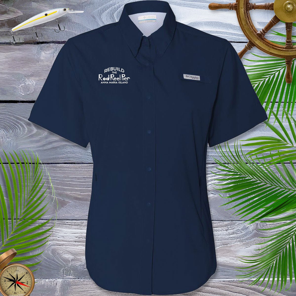 Women's Navy blue Fishing shirt with Fundraiser logo on a wooden surface with decorative elements
