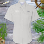 Beige short-sleeve shirt with brand logos on a wooden background with decorative elements.