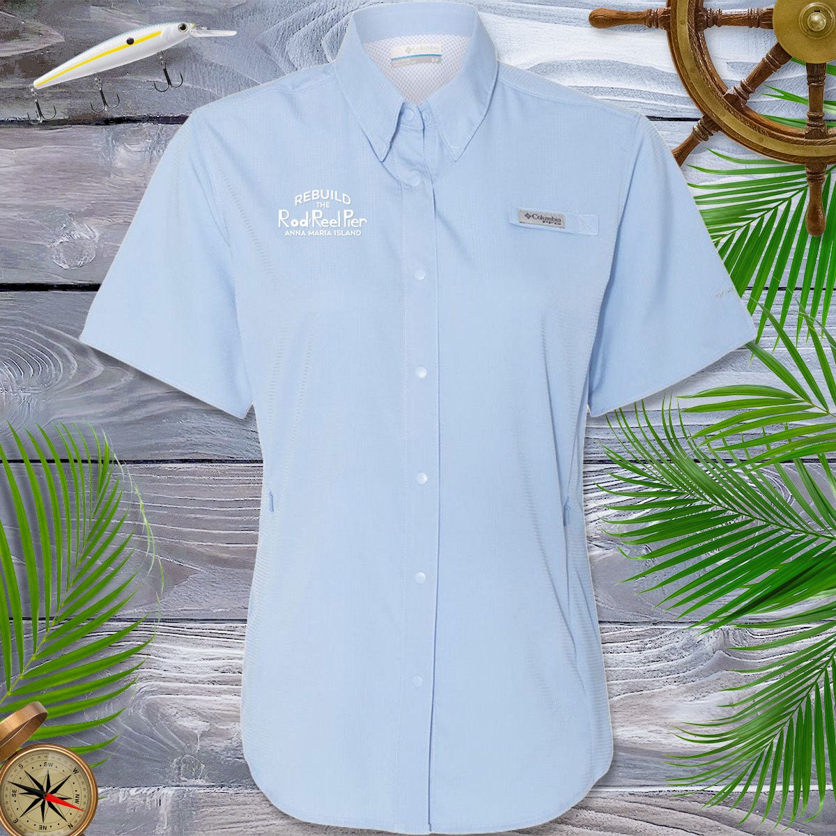Light blue short-sleeve shirt with brand logos on a wooden background with decorative elements.