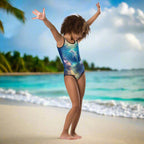 Girl's One Piece Swimsuit Featuring Cute Dolphin Art dancing on the beach in an island paradise