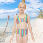 Young girl wearing a colorful striped swimsuit on a tropical island background