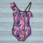 Seahorse Swimsuit with ruffles along the top over a rustic nautical wood background