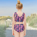 Girl wearing a colorful seahorse-patterned two-piece swimsuit on a sand dune path to the beach