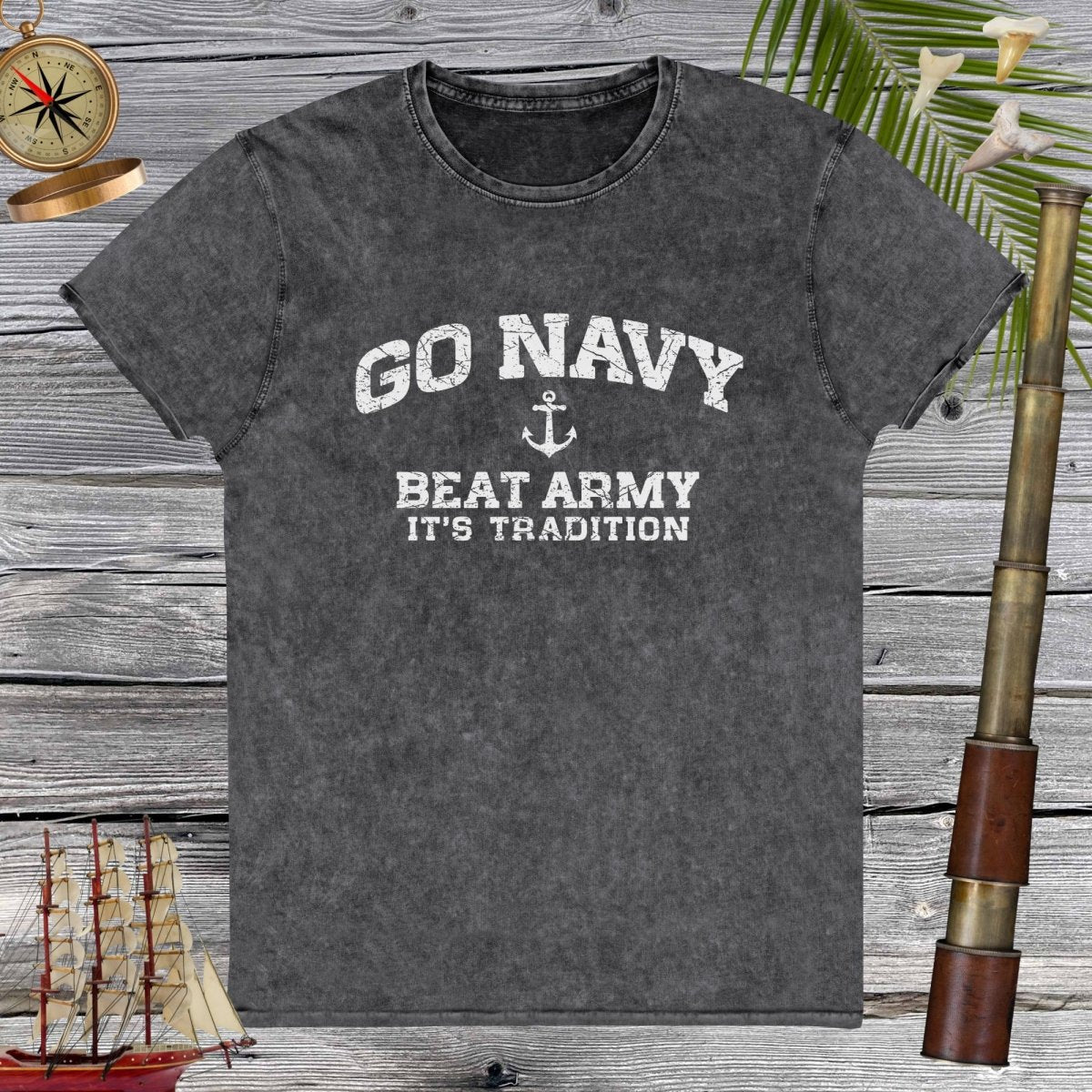 Gray t-shirt with 'Go Navy, Beat Army, It's Tradition' text on a wooden background with decorative elements.