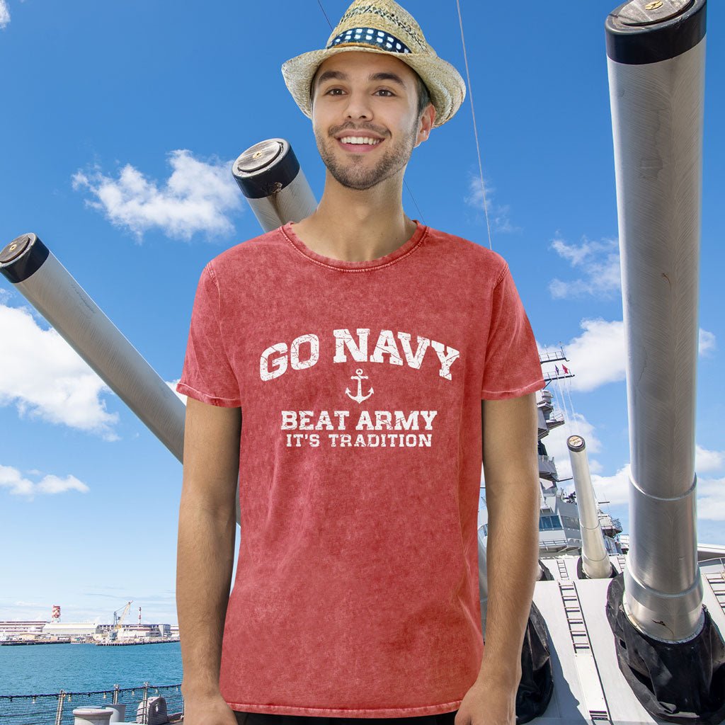 Man wearing a red 'GO NAVY BEAT ARMY IT'S TRADITION' t-shirt on a ship with blue sky and clouds in the background.