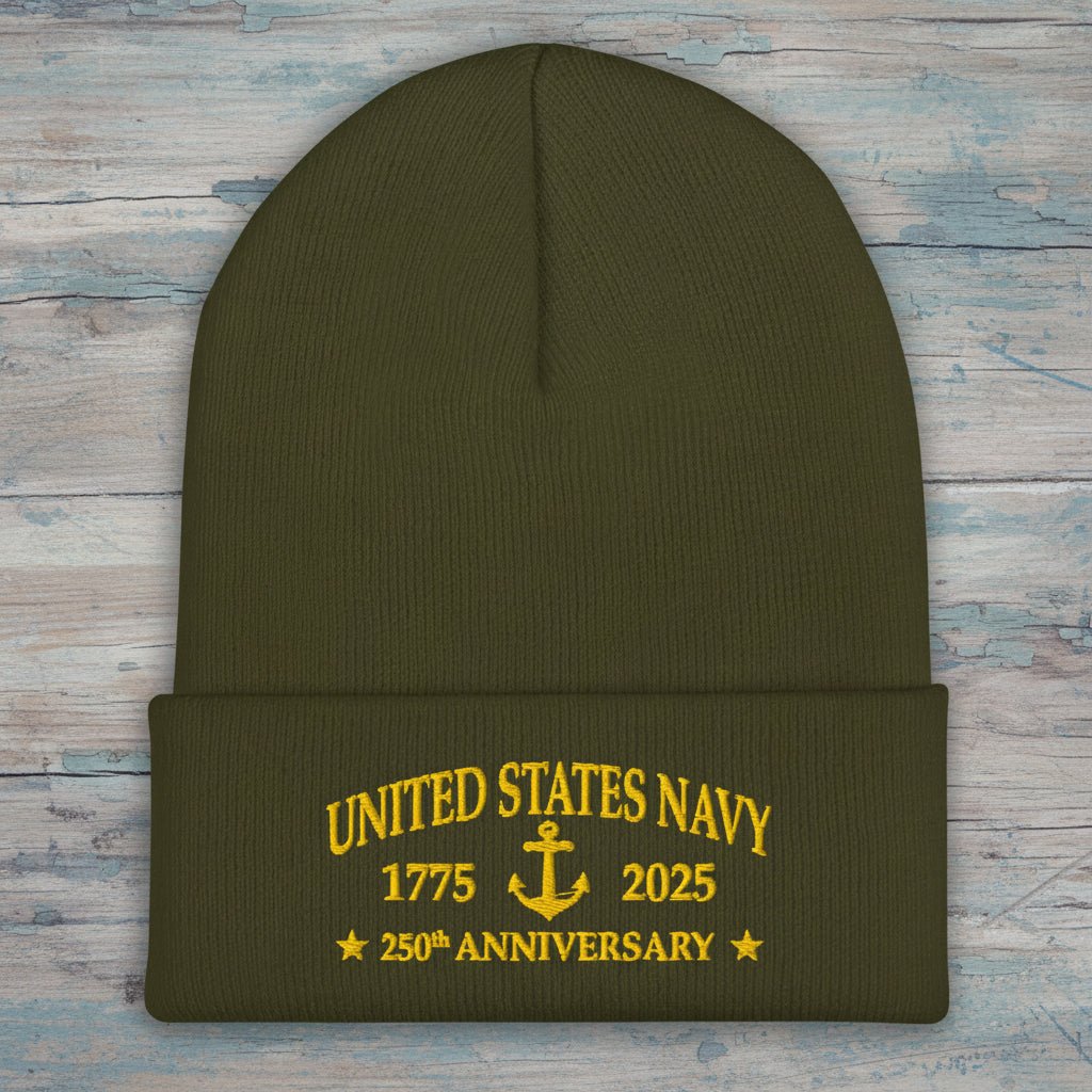 An olive green knit cuffed beanie with yellow embroidered text reading 'UNITED STATES NAVY 1775 2025 250th ANNIVERSARY' and an anchor motif on the front cuff.