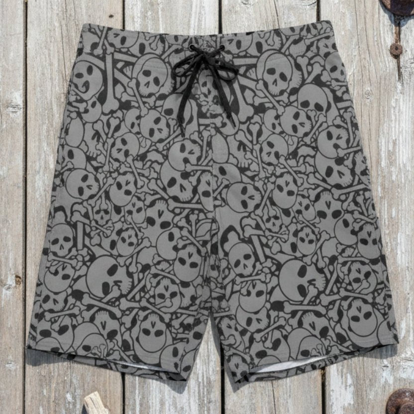 Gray shorts with black skull pattern on  laying down flat on a rustic nautical wood deck