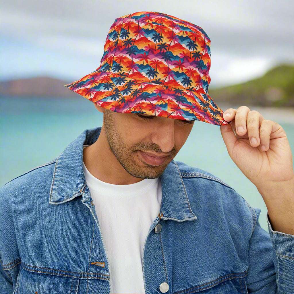 Guy wearing a Bongo Beachwear Bucket Hat with a colorful Hawaiian Style palm tree pattern standing on a beach in Waikiki. 