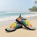 A pair of slip-on water shoes featuring a vibrant Hawaiian-Tropical floral and leaf print with yellow hibiscus flowers, green palm leaves, and red blossoms on a Waikiki Beach, finished with black trim and soles.