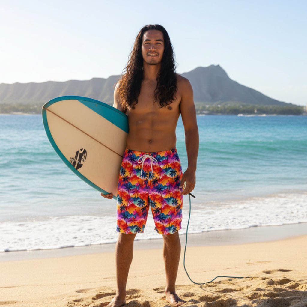Pacific Islander dude with long hair wearing tropical palm print board shorts, holding a surfboard on a Hawaiian Island Beach. 