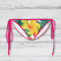 Bikini bottom with floral design and pink straps on a rustic wood background