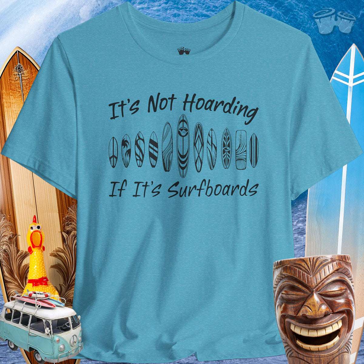Funny Surfboard Lover Unisex Tee in turquoise with the text 'It's Not Hoarding If It's Surfboards' against a beachy backdrop.