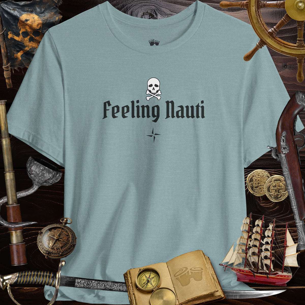 Feeling Nauti' Skull & Crossbone Unisex Pirate Tee on a wooden backdrop with pirate gear.