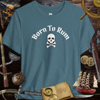 Born to Rum Jolly Roger Pirate Skull design on a casual Bella Canvas T-Shirt surrounded by pirate-themed props.