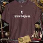 Pirate Captain unisex 3001c Bella Canvas tee displayed among pirate-themed items on a wooden surface.