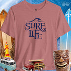 Surfer Life Tee featuring a wave design, ideal for beach lovers and surf enthusiasts, with vintage surf decor in the background.