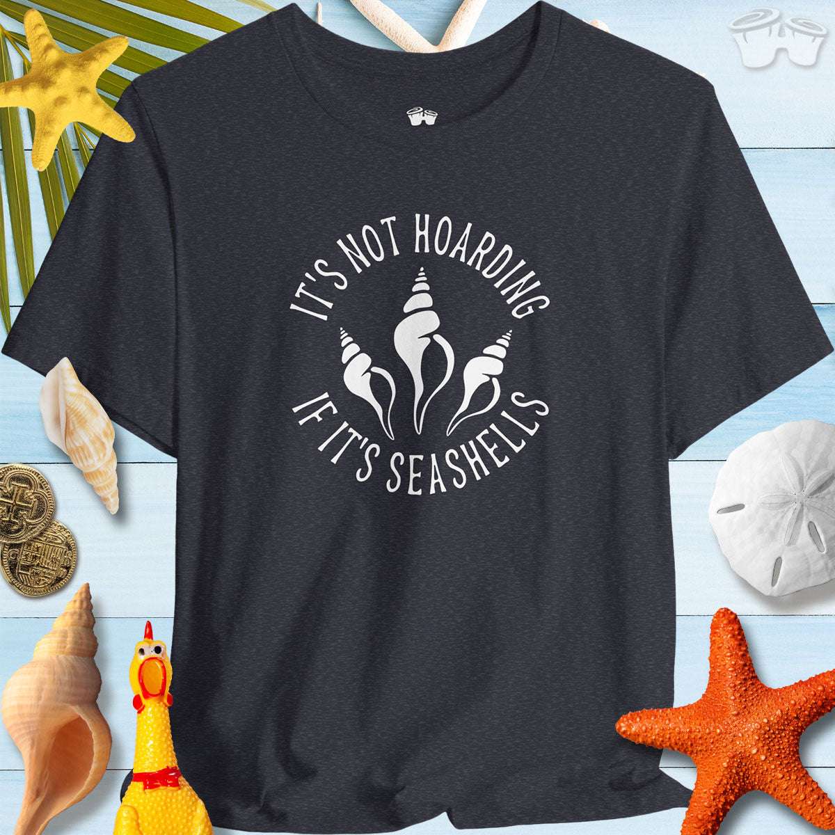 Beach Lover's Unisex Tee - 'It's Not Hoarding If It's Seashells' Shirt on a beach-themed background with seashells.