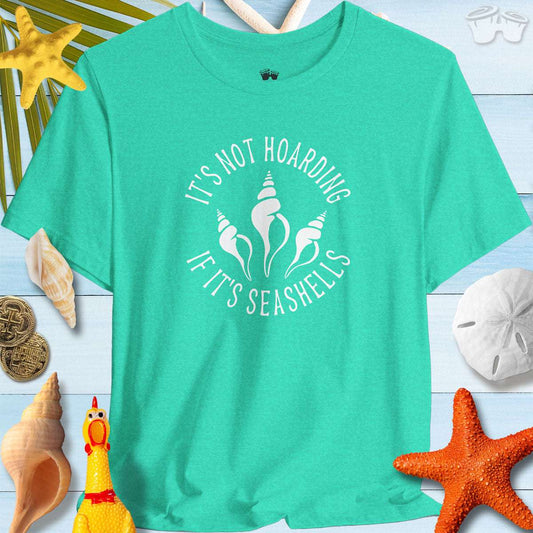 Beach Lover's Unisex Tee in teal with 'It's Not Hoarding If It's Seashells' print, surrounded by seashells and beach decor.