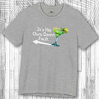 Gray t-shirt with a graphic of a Margarita and the text: "It's His Own Damn Fault" on a wooden surface