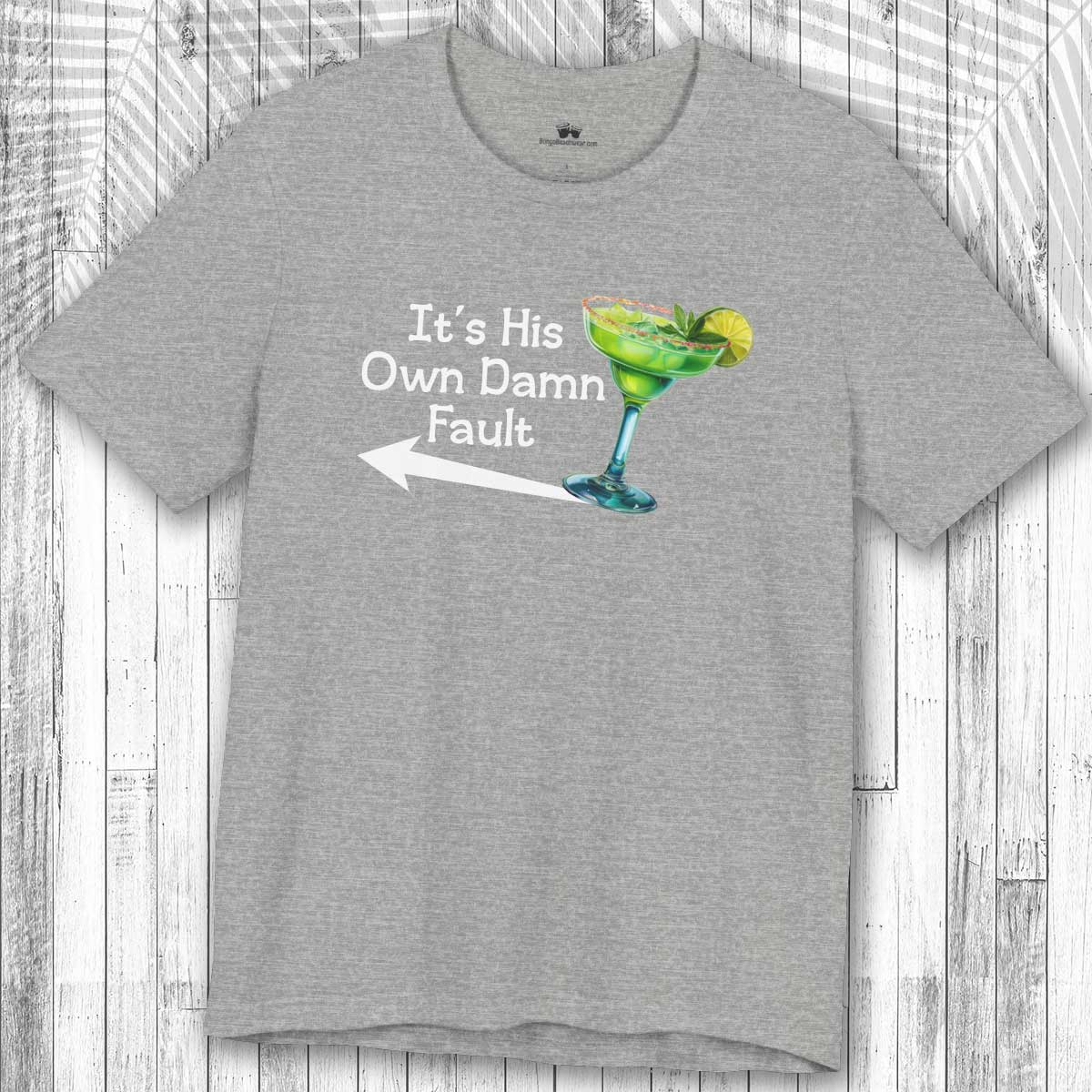 Gray t-shirt with a graphic of a Margarita and the text: "It's His Own Damn Fault" on a wooden surface