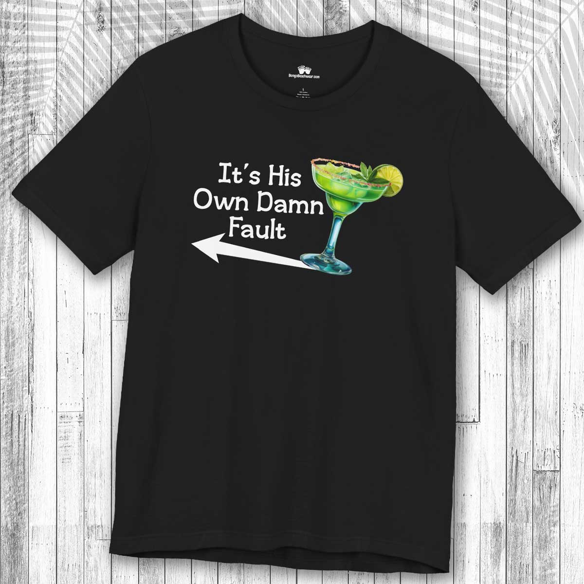 Black t-shirt with a graphic of a Margarita cocktail and the text:  "It's His Own Damn Fault" on a wooden surface