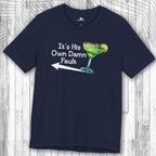 Navy blue t-shirt with a graphic of a Margarita  and text "It's His Own Damn Fault" on a wooden surface