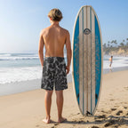 Young surfer dude wearing black board shorts with gray sharks on La Jolla Beach