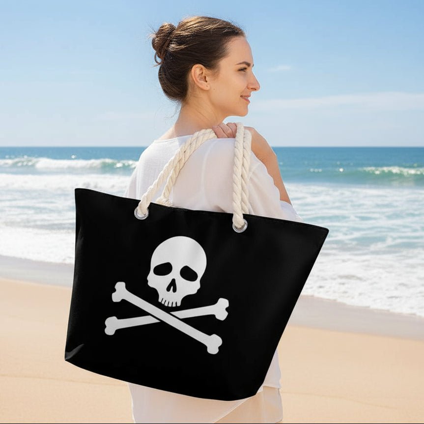 Person carrying a black tote bag with a skull and crossbones design in a park.