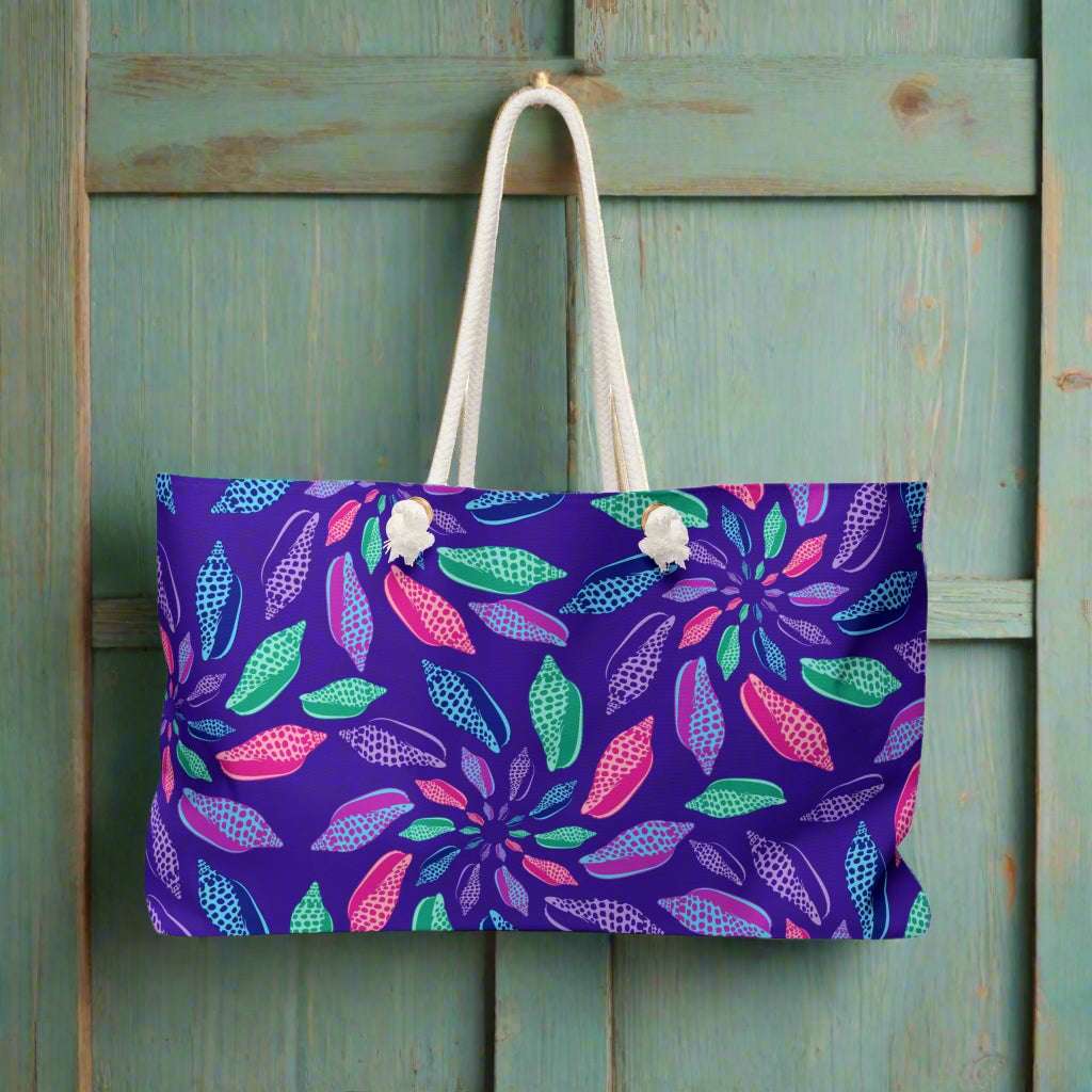Deep Blue beach bag with colorful Junonia seashell pattern hanging from the wall of a beachside tiki bar