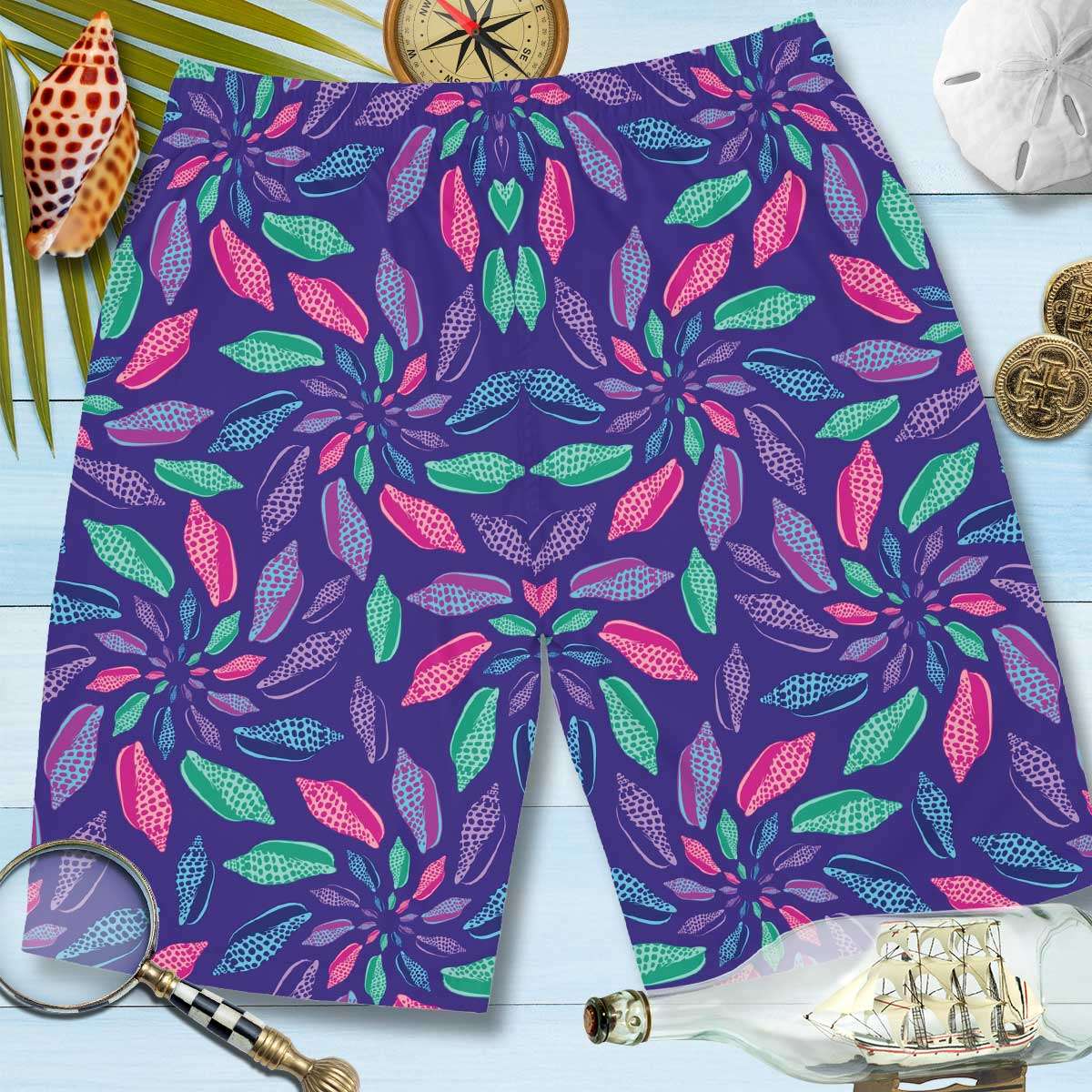 Back of Men's Boardshorts lying on nautical wood along with a compass, a sand dollar, 2 gold coins, a ship in a bottle, a magnifying glass and a Junonia.