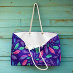 Oversized tote bag with a colorful junonia seashell pattern hanging from a hook in the rustic teal wall of seaside surf shack