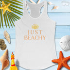 Just Beachy Women's Tank Top on a beachy background with seashells and tropical elements, perfect for summer vibes.