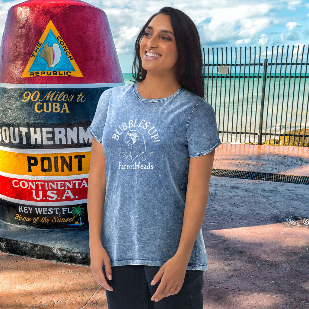 Woman wearing a blue t-shirt with text standing next to a large sign in Key West, Florida.