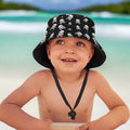 Child wearing a black Jolly Roger Bucket Hat with random skull and crossbones pattern on a Caribbean island beach