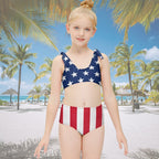 Child wearing a swimsuit with American flag design on a tropical beach resort