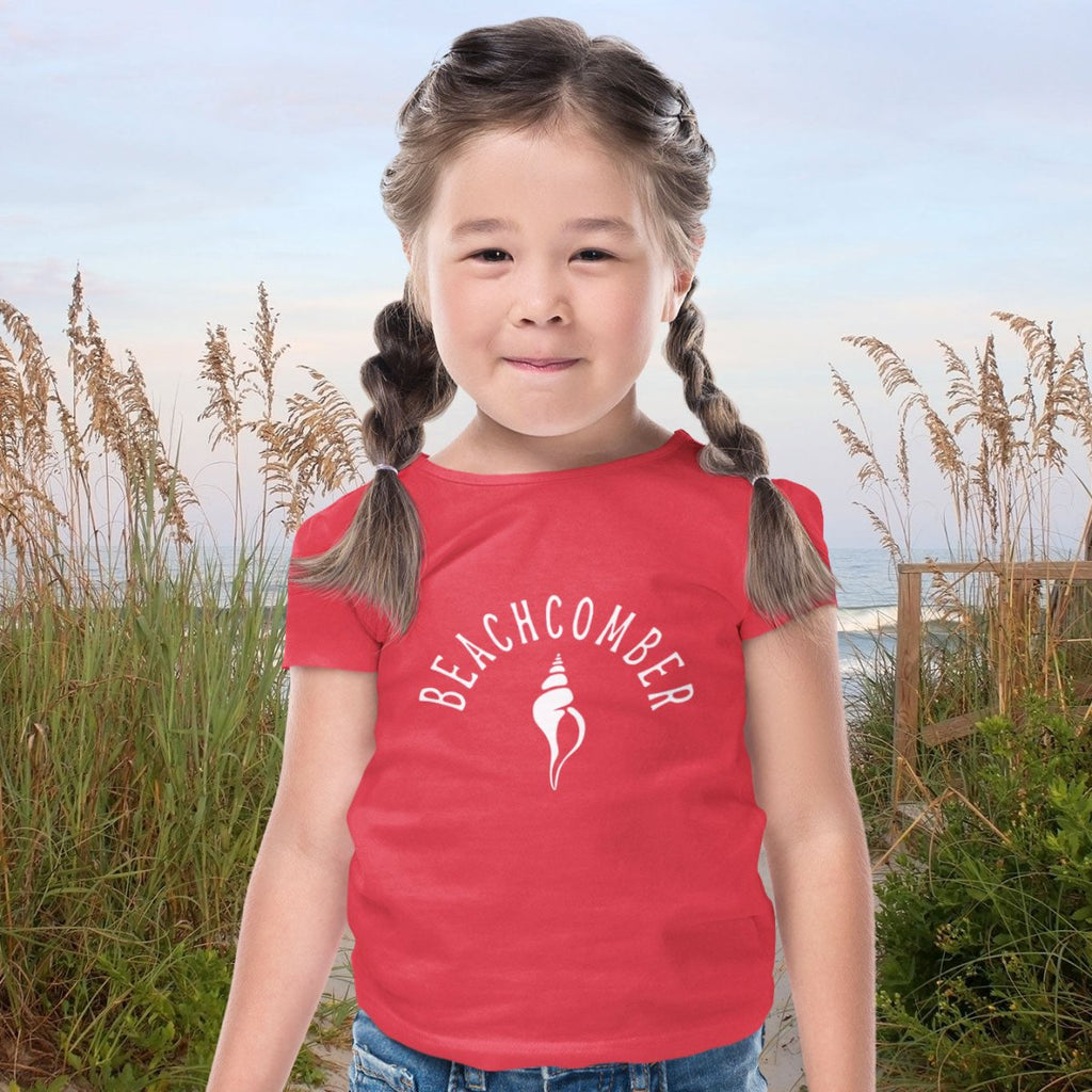 Toddler wearing beachcomber tee standing in front of stand dunes.
