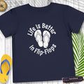 Navy blue t-shirt with 'Life is Better in Flip-Flops' text and flip-flop graphics on a wooden surface.