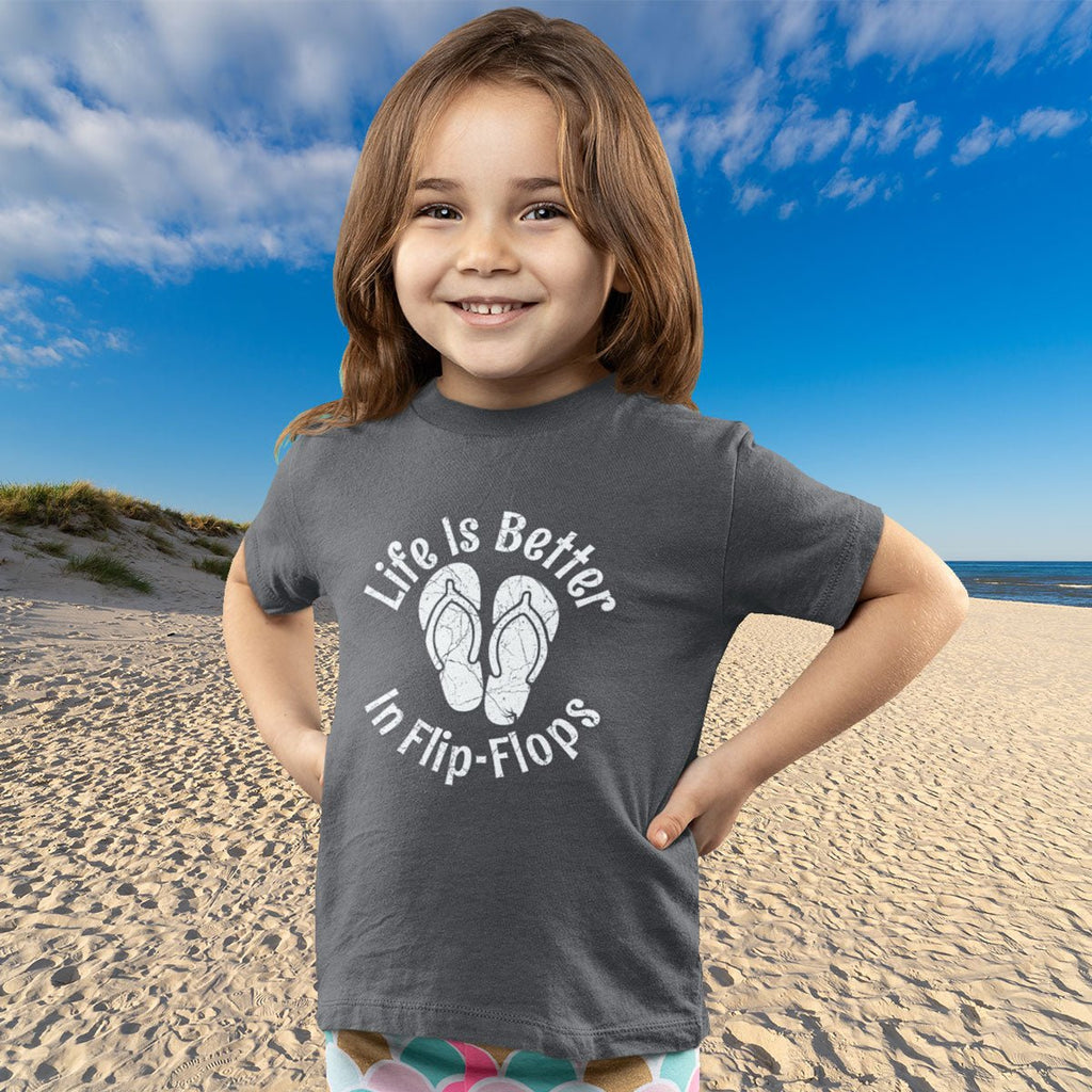 Child wearing a t-shirt with 'Life is Better in Flip-Flops' text on a beach
