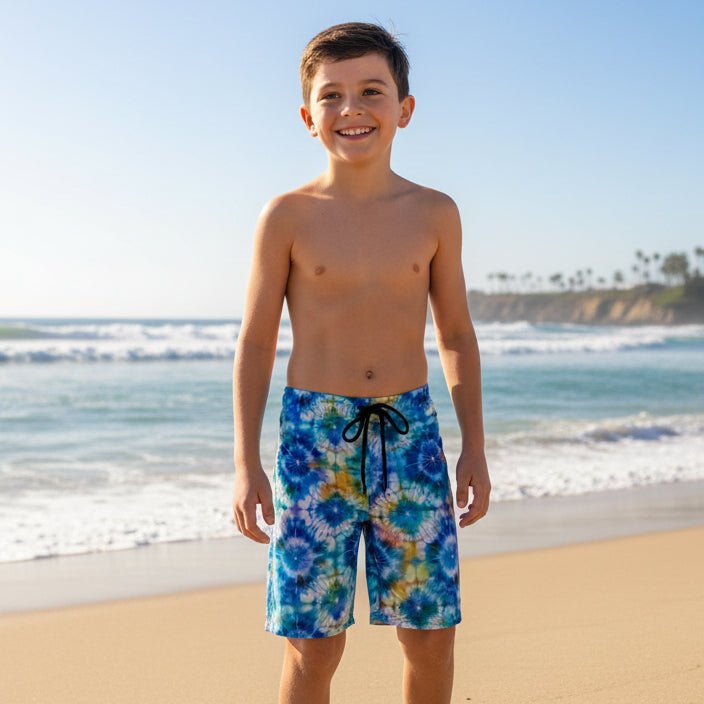 Young boy wearing colorful Shibori Tie-Dye swim shorts on a beach.